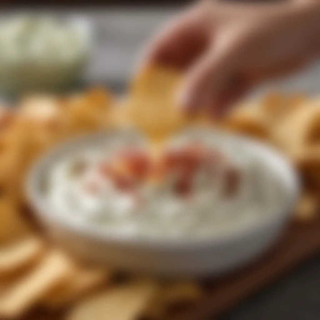 A hand elegantly scooping ranch dip with a crispy chip.